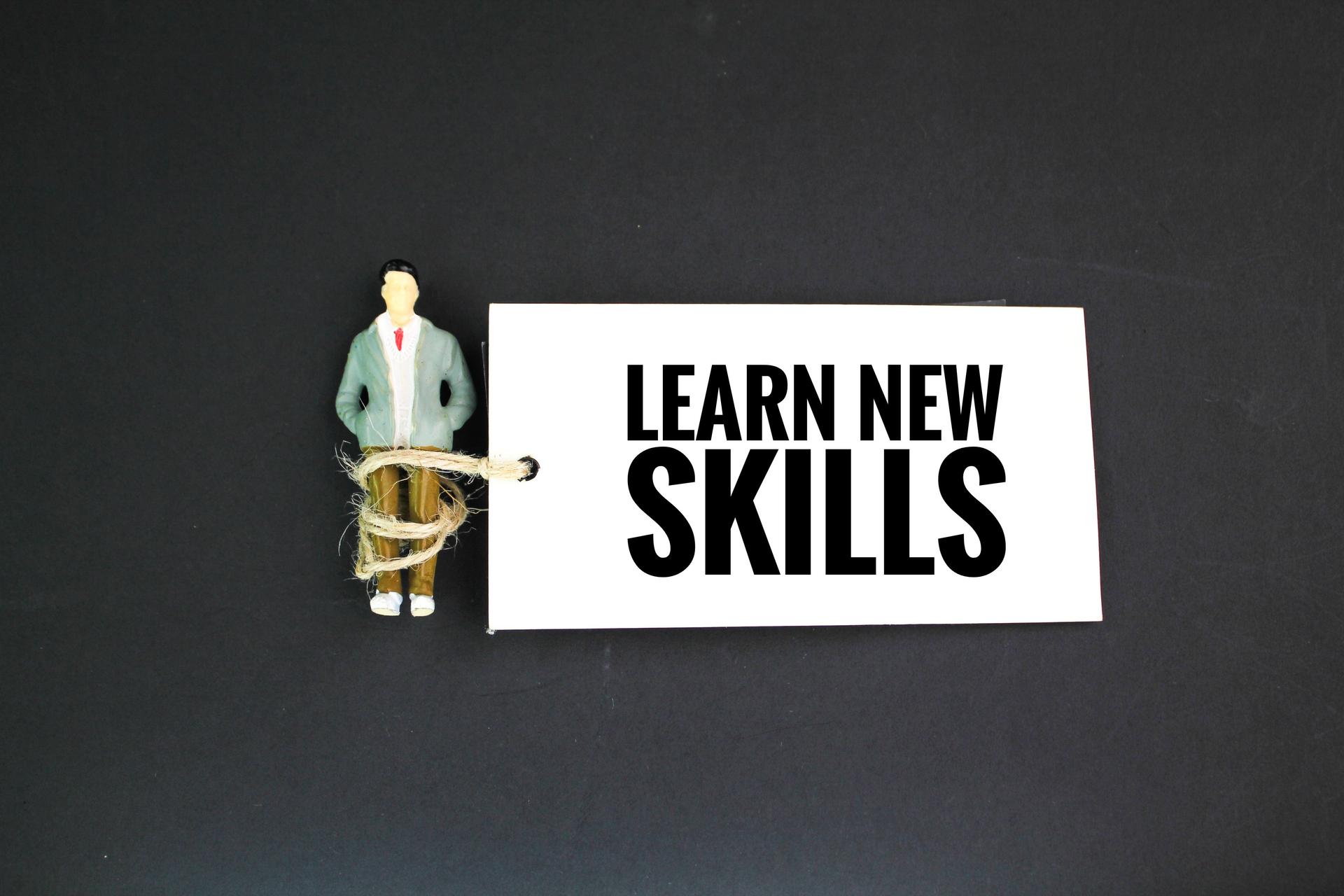 miniature people and paper tags with the words learn new skills. the concept of hidden skills
